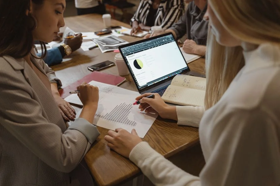 Business analysis in a modern office, shown with charts and graphs on a laptop.